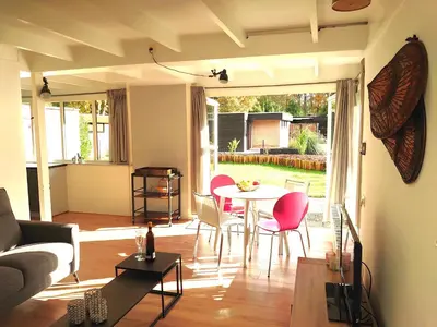 a living room with a table and chairs at Zonnige vrijstaande bungalow in prachtige omgeving! in Rekem