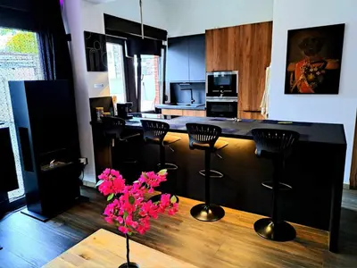 a kitchen with a bar with stools and pink flowers at Chambre dans une maison d'hote in Liège