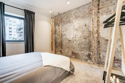 a bedroom with a brick wall and a bed at L'appart Léon, avec parking gratuit in Liège