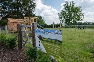 a sign on a fence next to a playground at NIEUW - De Grenspaal WEST 6P 5 min Maastricht - Sauna - Laadpaal in Riemst
