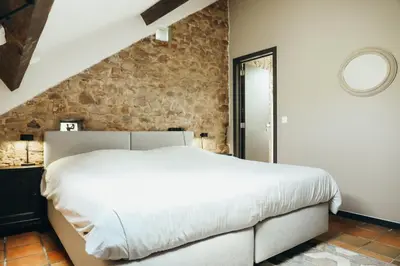 a bedroom with a white bed and a stone wall at La Terrasse du Pré by WelcHome in Verviers