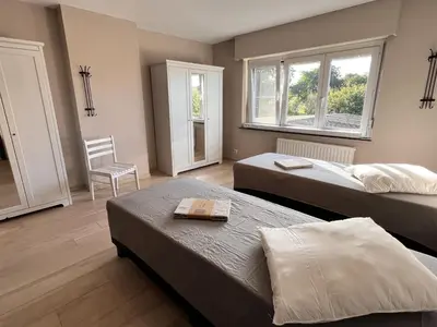 a bedroom with two beds and a chair and two windows at 8P 4B Beautiful house with 4 bedrooms in Hees in Bilzen