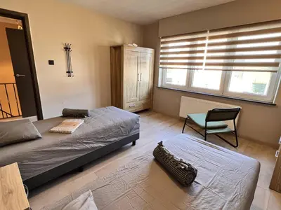 a bedroom with two beds and a chair in it at 8P 4B Beautiful house with 4 bedrooms in Hees in Bilzen