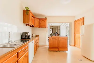 a kitchen with wooden cabinets and a white refrigerator at Beautiful mansion with swimming pool and jacuzzi in Bilzen