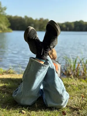 a person with their feet up in a blanket next to a lake at Vakantiewoning Waag in Rekem