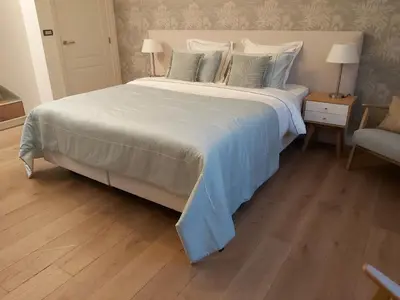 a bedroom with a large white bed and a chair at B&B Asmara in Maasmechelen