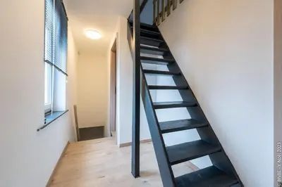 a black spiral staircase in a room with a window at Le Gîte du Moulin - Modernity & Elegance - jacuzzi in Oupeye