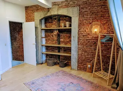 a room with a brick wall with shelves and a rug at La Tour by WelcHome in Verviers