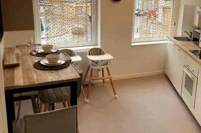 a kitchen with a table and chairs and two windows at La Tour by WelcHome in Verviers