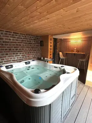a hot tub in a room with a brick wall at Cosy@Beauty in Petit-Rechain