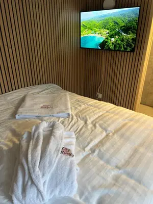 a bed with towels on it with a tv on the wall at Cosy@Beauty in Petit-Rechain