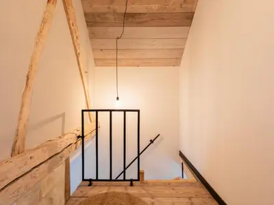 a staircase in a house with wooden ceilings and a light fixture at Maison Cuberdon in Riemst