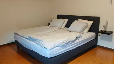 a bed with white sheets and pillows in a room at Brelaarheide in Houthalen-Helchteren
