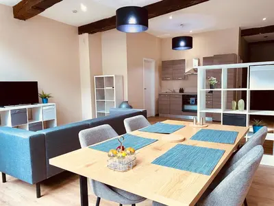 a dining room with a table and a blue couch at The Mind Box 2 in Liège
