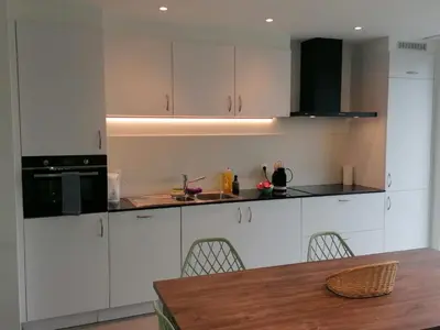 a kitchen with white cabinets and a wooden table at Rent & Relax: Vitrabelle in Lommel