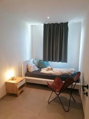 a room with a bed with a window and a chair at Rent & Relax: Vitrabelle in Lommel