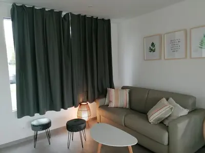 a living room with a green couch and two stools at Rent & Relax: Vitrabelle in Lommel