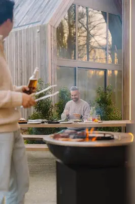 a man sitting at a table in front of a fire at Woodz Lodges in Heusden - Zolder