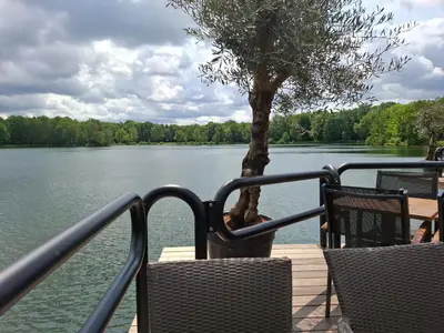 a dock with two chairs and a tree on a lake at Vrijstaande vakantiebungalow met optimale privacy!! in Rekem