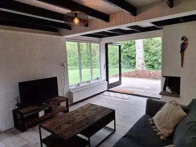 a living room with a couch and a tv at Vrijstaande vakantiebungalow met optimale privacy!! in Rekem