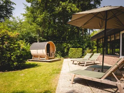 a yard with chairs and an umbrella and a sauna at Boshuisje Rekem - Alma with private sauna in Lanaken