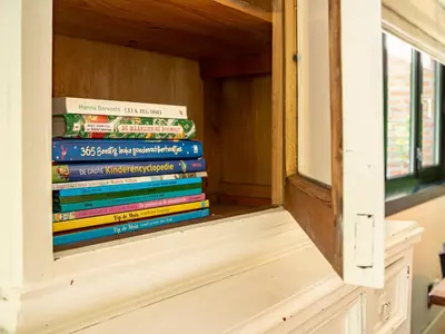 a stack of books sitting on a window sill at Boshuisje Rekem - Alma with private sauna in Lanaken