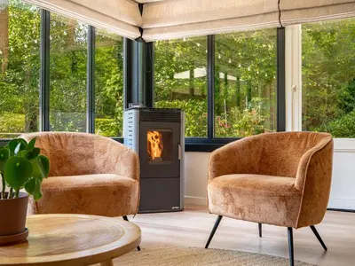 two chairs in a living room with a fireplace at Boshuisje Rekem - Alma with private sauna in Lanaken