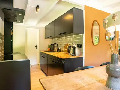 a kitchen with black cabinets and a wooden table at Boshuisje Rekem - Alma with private sauna in Lanaken