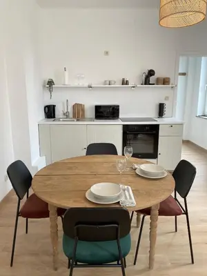 a dining room table with chairs and a kitchen at Cosy Alba plein centre Visé in Visé