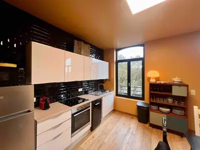 a large kitchen with white cabinets and a window at Le rétro chic - Grand Duplex pour 6 dans le centre in Liège