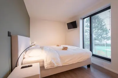 a bedroom with a bed and a large window at NIEUW - De Grenspaal OOST 7P - 3SLPK - SAUNA - LAADPAAL in Riemst