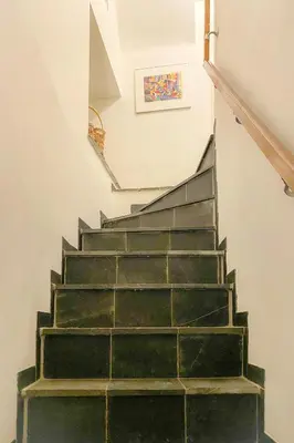a stairway with green steps and a picture on the wall at Authentic apartment in Voeren in Voeren