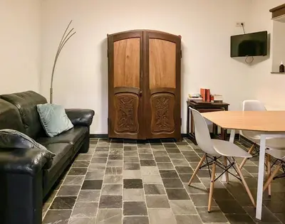 a living room with a couch and a table and a wooden door at Authentic apartment in Voeren in Voeren