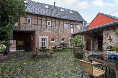 an outdoor patio with tables and chairs and a building at Authentic apartment in Voeren in Voeren