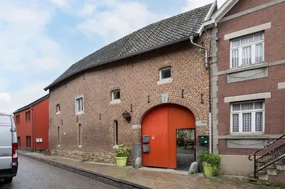 a brick building with a red door on a street at Beautiful appartment in Voeren in Voeren