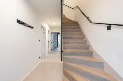 a staircase in a house with white walls and wooden floors at NIEUW De Grenspaal ZUID 2slpk - 4P - SAUNA - LAADPAAL in Riemst