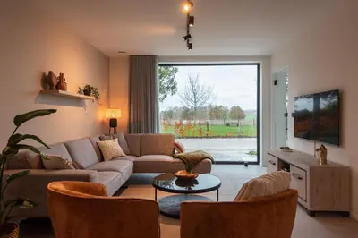 a living room with a couch and a large window at NIEUW De Grenspaal NOORD 6P - 3SLPK 5 min Maastricht - SAUNA - LAADPAAL in Riemst