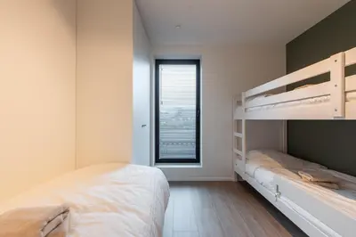 a bedroom with two bunk beds and a window at NIEUW De Grenspaal NOORD 6P - 3SLPK 5 min Maastricht - SAUNA - LAADPAAL in Riemst