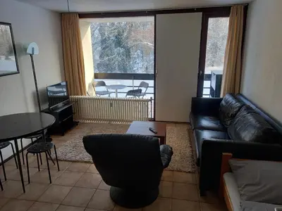 a living room with a couch and a table and a balcony at Ap22 Nature Ardennes Economy class apartment in La Calamine
