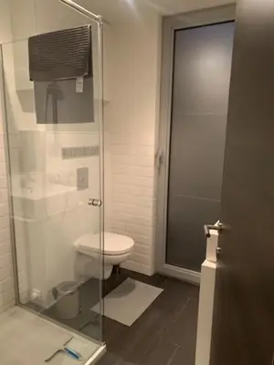 a bathroom with a toilet and a glass shower door at 't Veldje in Tongeren
