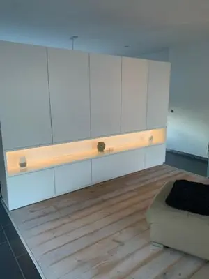a kitchen with white cabinets and a wooden floor at 't Veldje in Tongeren