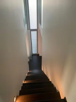 a hallway with stairs with a window and lights at 't Veldje in Tongeren