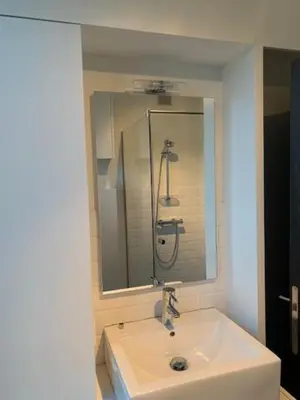 a white bathroom with a sink and a mirror at 't Veldje in Tongeren