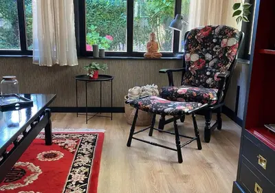 a living room with a chair and a table at Spechthuisje, 4-pers bungalow in Rekem in Lanaken