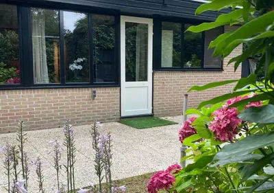 a house with a white door and some flowers at Spechthuisje, 4-pers bungalow in Rekem in Lanaken