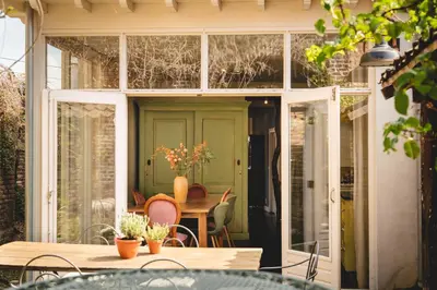 a sliding glass door on a patio with a table at Maas Suites - The French House in Lanaken