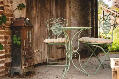 a table and two chairs sitting next to a fence at Maas Suites - The French House in Lanaken