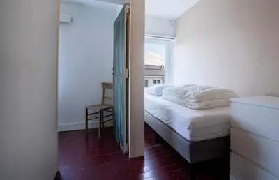 a bedroom with a bed and a chair and a window at Maas Suites - The French House in Lanaken