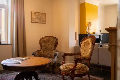 a living room with two chairs and a table at Maas Suites - The French House in Lanaken