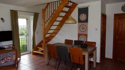 a dining room with a wooden table and a staircase at Appartement Hoeve Espewey - Leisure only in Hombourg